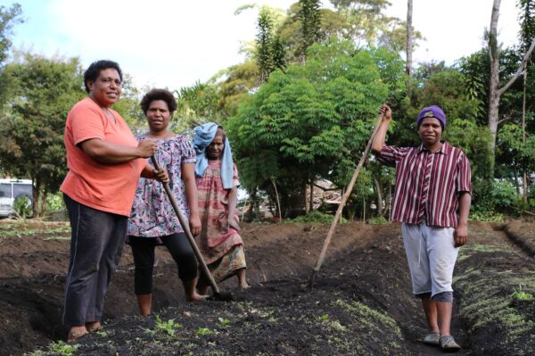 In a garden, three women collaborate and share local insights in market development.