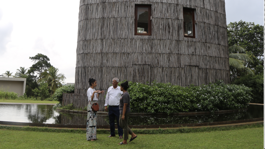 Three people talking outside a nature-inspired building during a low-carbon tourism visit in Sri Lanka.