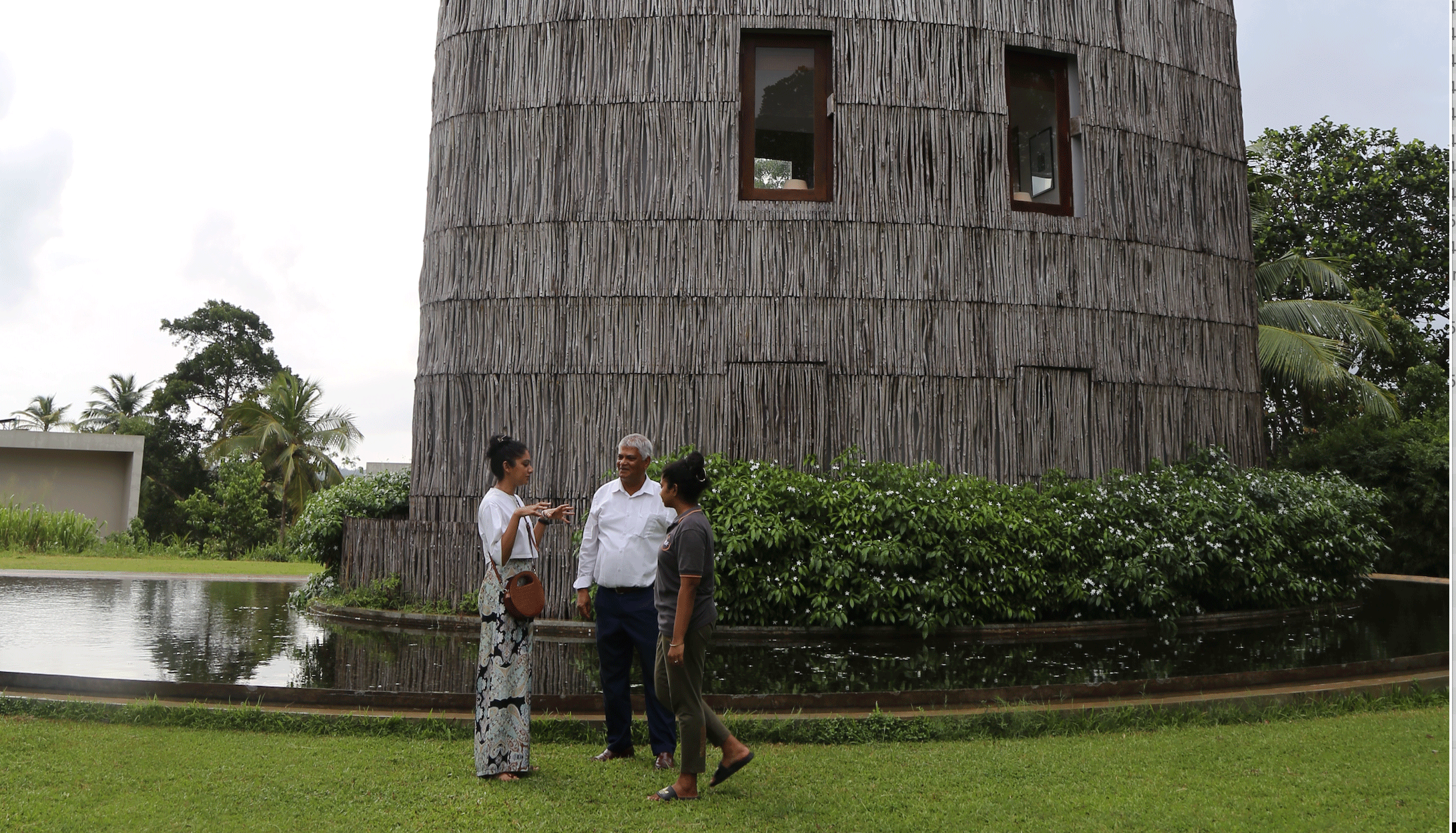Three people talking outside a nature-inspired building during a low-carbon tourism visit in Sri Lanka.