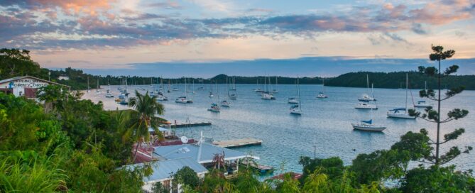 Sailboats anchored in a sheltered bay in Tonga at sunset.