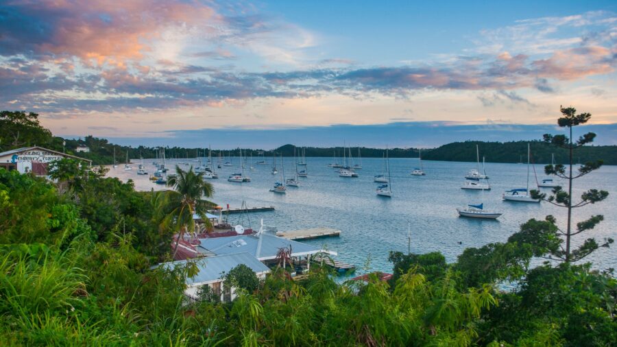 Sailboats anchored in a sheltered bay in Tonga at sunset.