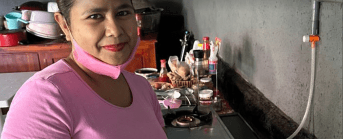 Woman standing beside a gas stove in a kitchen, illustrating renewable energy from pig manure.