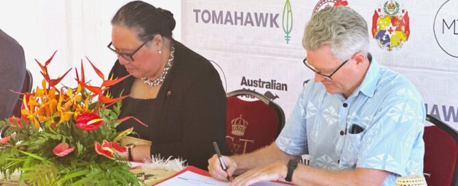 A men and a woman at a table, signing papers for a yacht cruising guide collaboration with Tonga Tourism Authority.