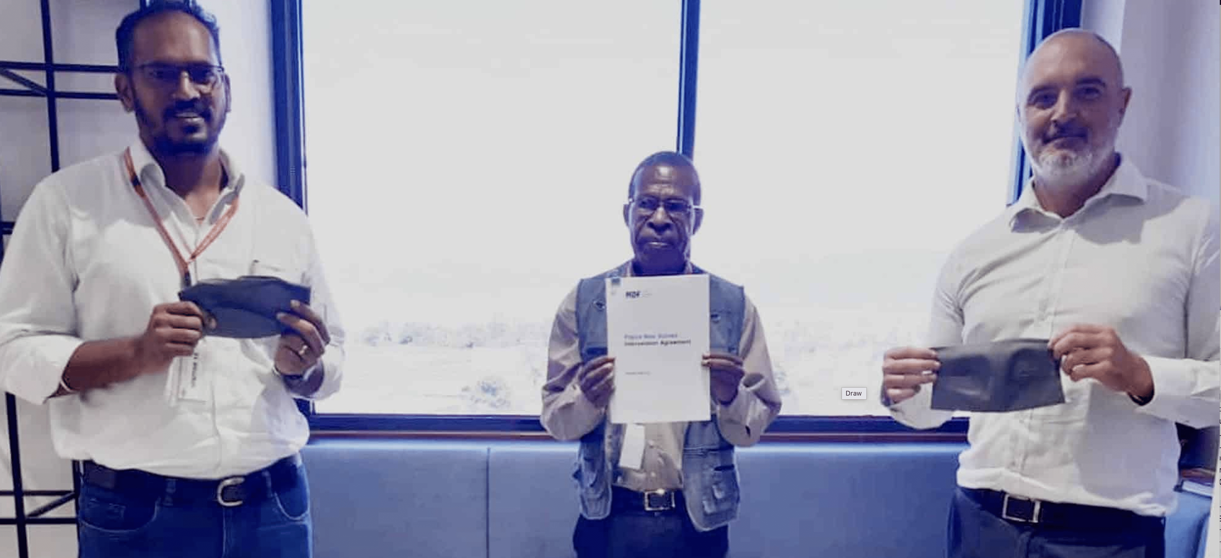 Three representatives holding agreement documents and face masks at an MDF and Outspan event in PNG.
