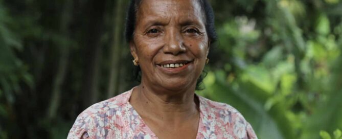 Joana de Sá, an older Timorese’s pig farmer, smiles at the camera, thinking of the benefits of easier feeding practices.