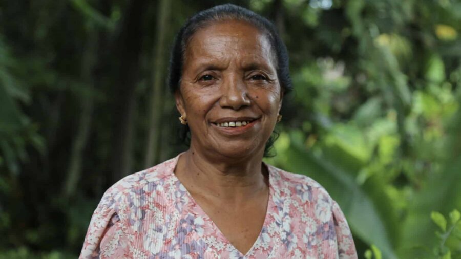 Joana de Sá, an older Timorese’s pig farmer, smiles at the camera, thinking of the benefits of easier feeding practices.