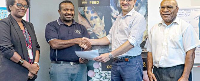 Representatives shaking hands in front of an MDF and PHAMA Plus partnership banner in Papua New Guinea.