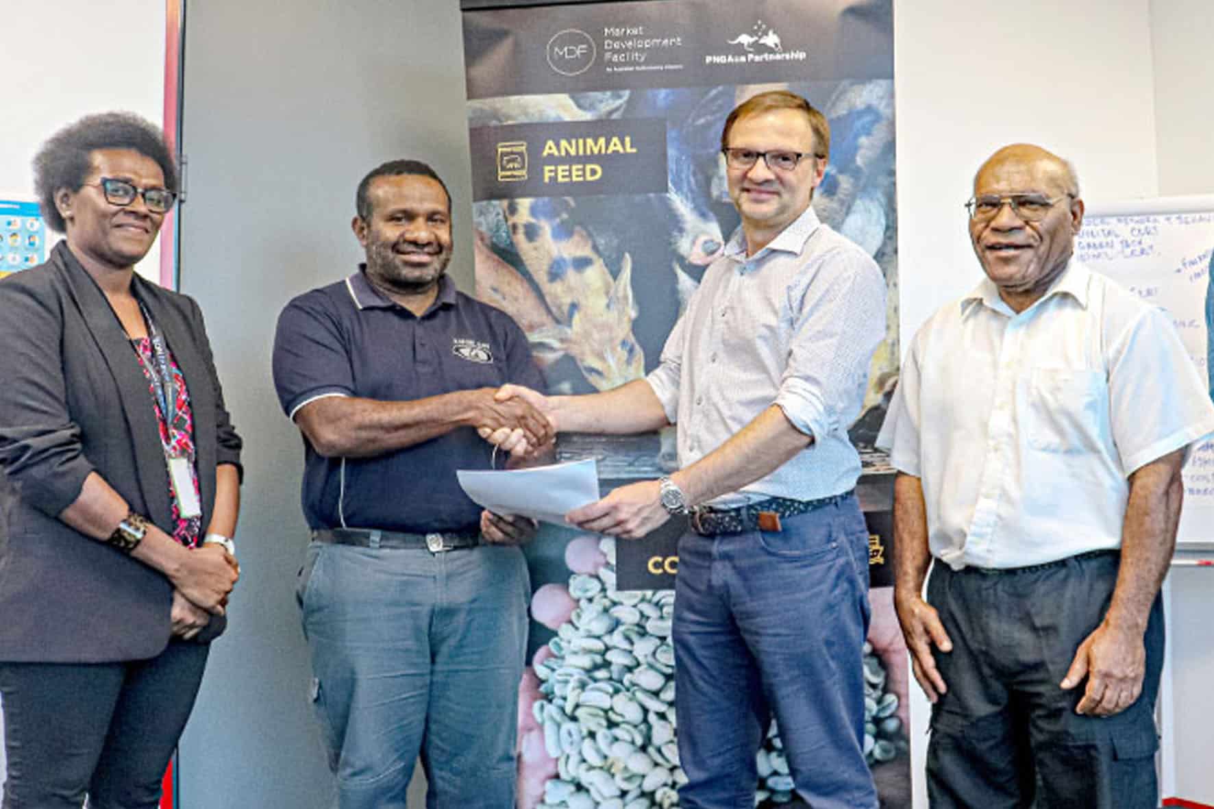 Representatives shaking hands in front of an MDF and PHAMA Plus partnership banner in Papua New Guinea.