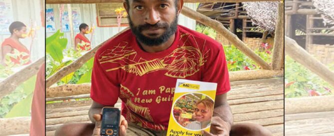 Farmer holding a mobile phone and MiCard loan product flyer in Papua New Guinea.