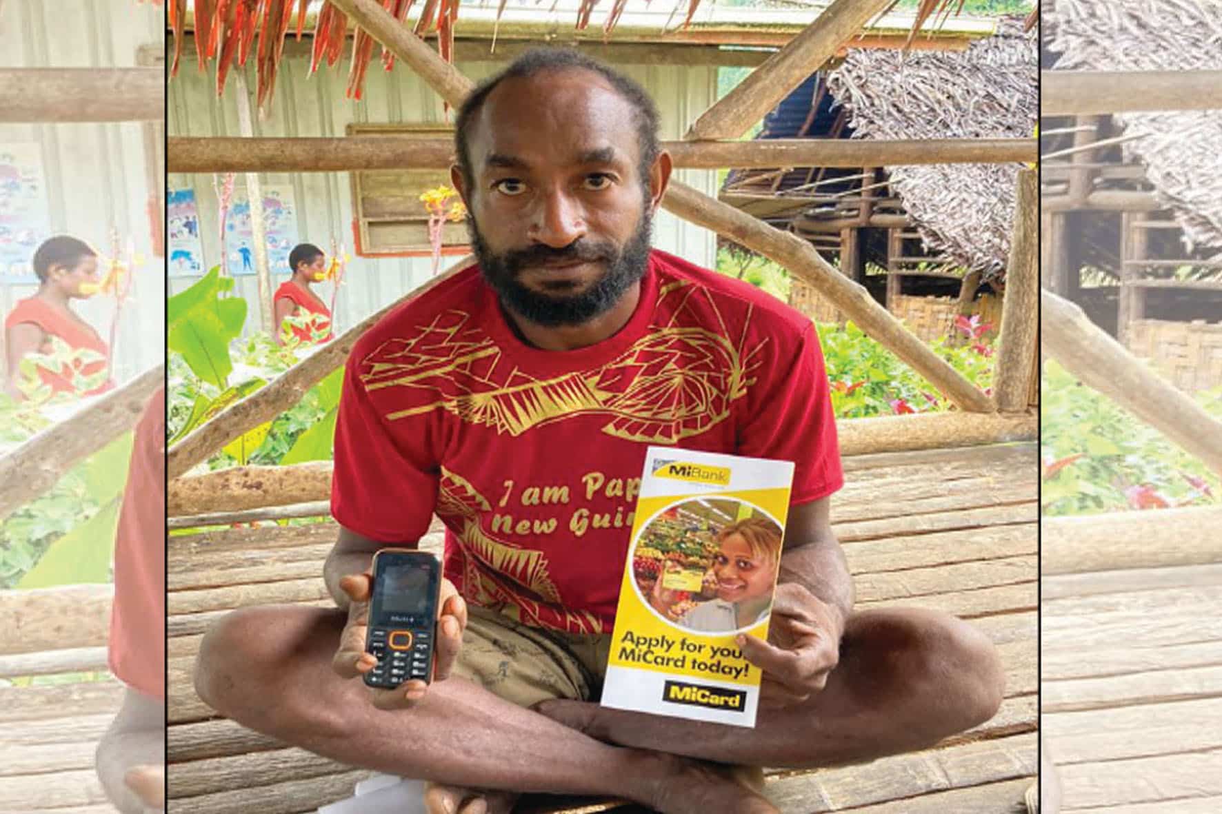 Farmer holding a mobile phone and MiCard loan product flyer in Papua New Guinea.
