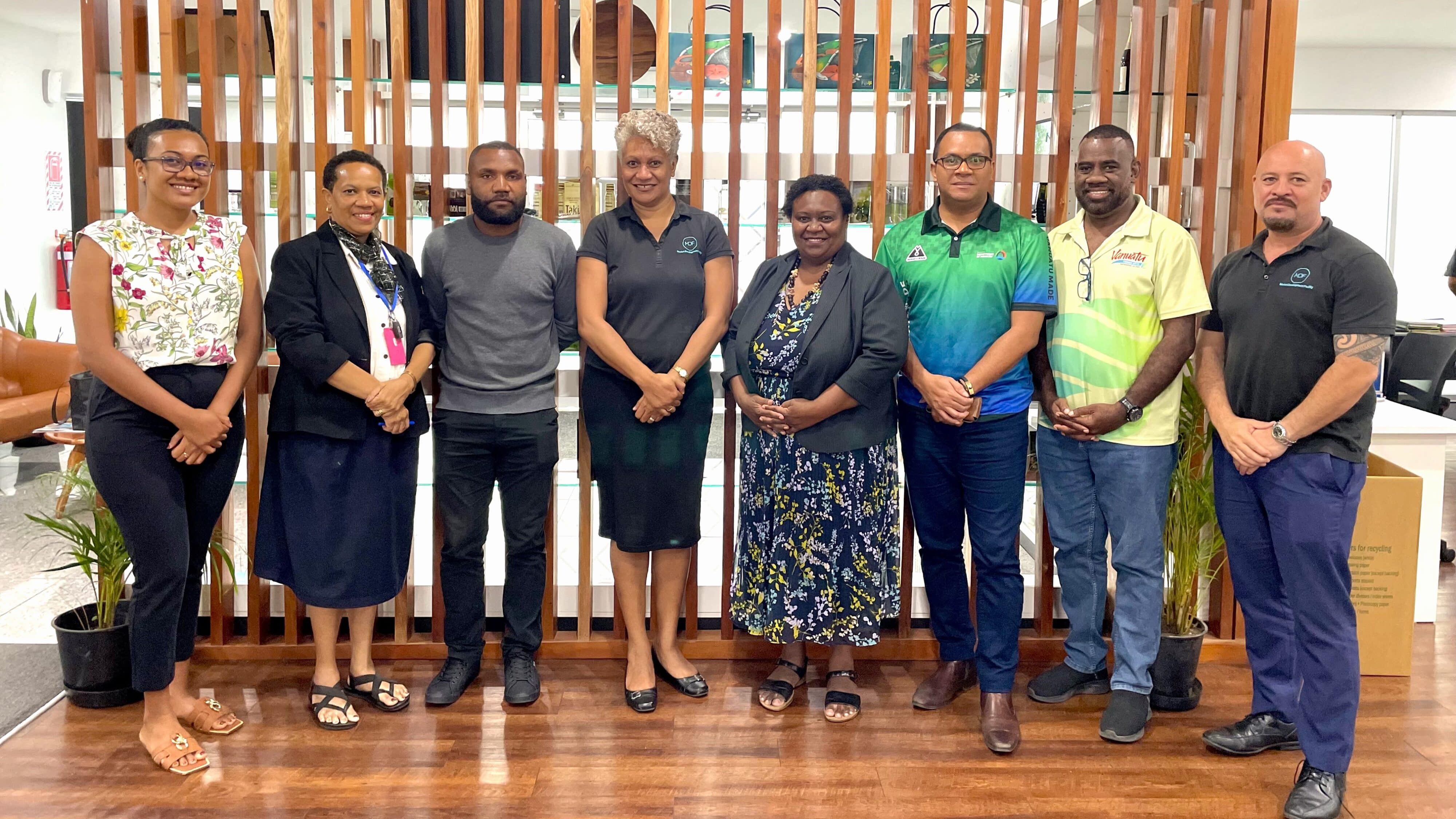 A diverse group stands before a wooden wall, facilitating discussions on regional knowledge sharing in the yachting sector.